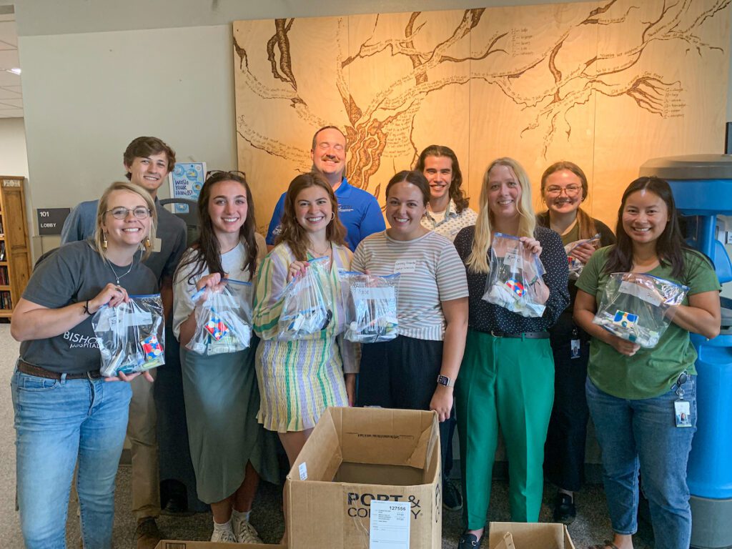Interns smile with hygiene bags assembled for the Bishop Dudley Hospitality House